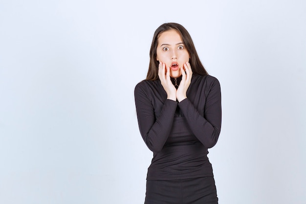 Mulher jovem com roupas pretas parece apavorada e assustada