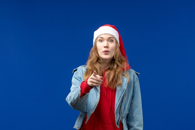 Mulher jovem com tampa vermelha de natal na mesa azul, emoção de natal, vista frontal