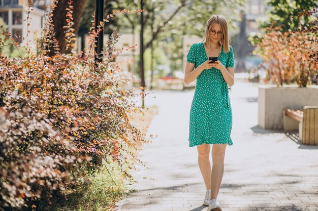 Mulher jovem com telefone andando na rua