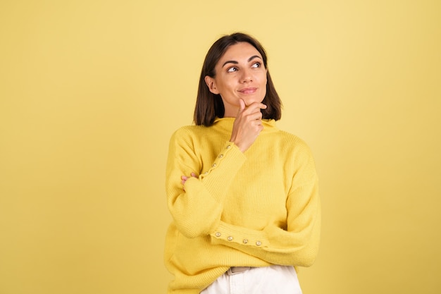 Mulher jovem com um suéter amarelo quente tocando seu queixo