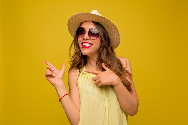 Mulher jovem com um vestido amarelo com chapéu e óculos de sol