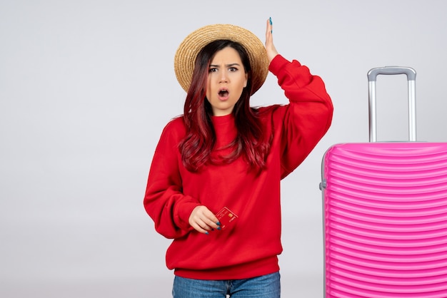 Mulher jovem com uma bolsa rosa segurando o cartão do banco na parede branca de frente