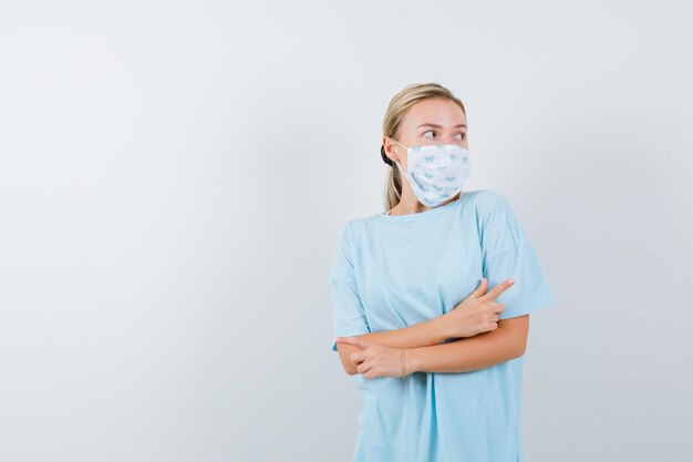 Mulher jovem com uma camiseta azul e uma máscara médica