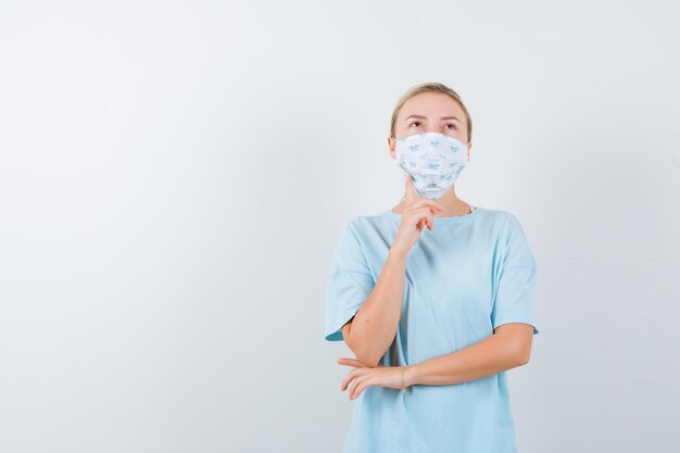 Mulher jovem com uma camiseta azul e uma máscara médica