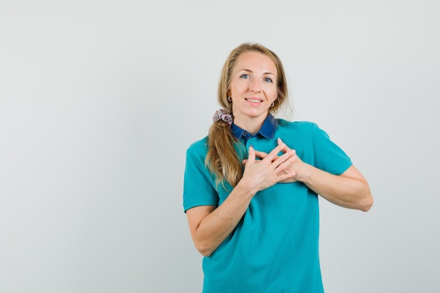 Mulher jovem com uma camiseta de mãos dadas no peito e parecendo grata