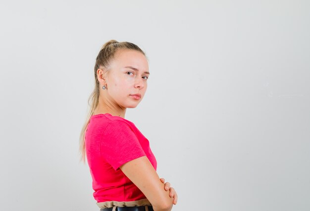 Mulher jovem com uma camiseta em pé com os braços cruzados e parecendo desolada