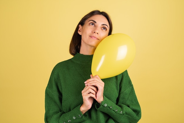 Mulher jovem com uma camisola verde a sorrir com um balão de ar