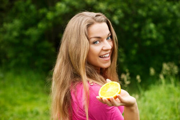 Mulher jovem com uma fatia de laranja