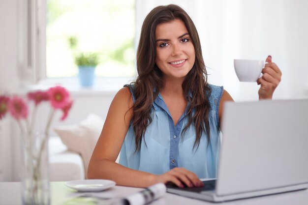 Mulher jovem com uma xícara de café e um laptop