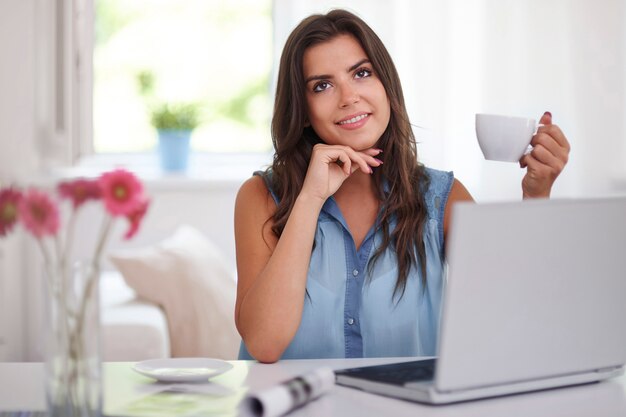 Mulher jovem com uma xícara de café e um laptop