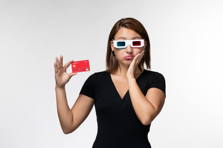 Foto grátis mulher jovem com vista frontal segurando o cartão do banco vermelho em óculos de sol d na superfície branca