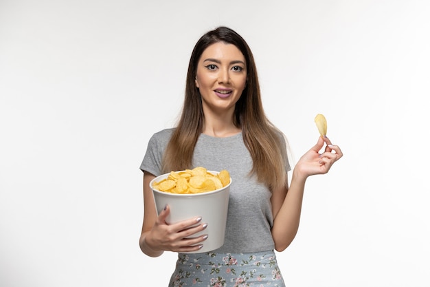 Mulher jovem comendo cips e assistindo filme na superfície branca de frente