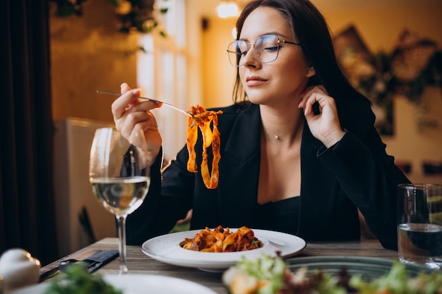 Mulher jovem comendo macarrão em um café