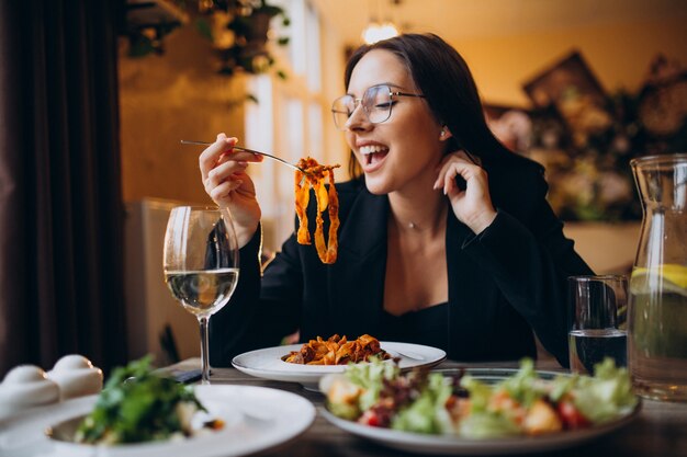 Mulher jovem comendo macarrão em um café