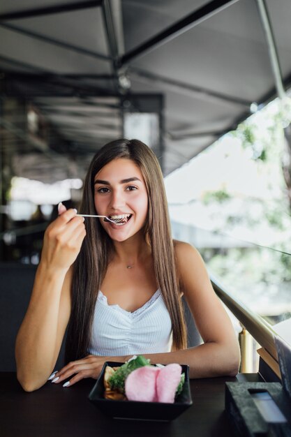 Mulher jovem comendo uma refeição saudável sentada no belo interior