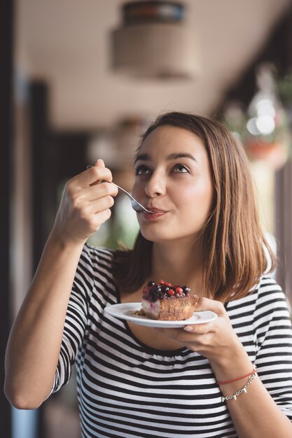 Mulher jovem, comer, cheesecake morango