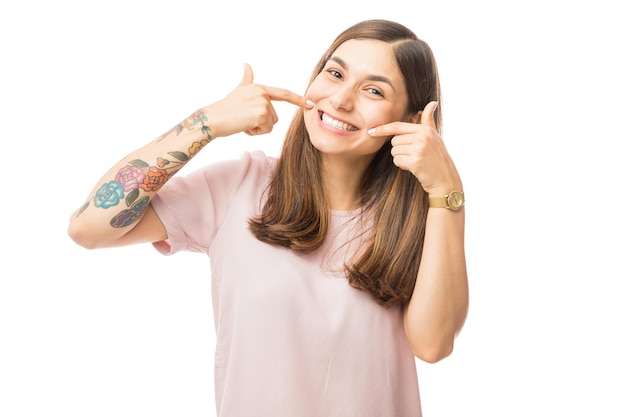 Mulher jovem confiante mostrando seus dentes brancos retos perfeitos contra o fundo branco