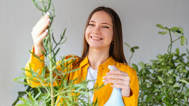 Mulher jovem cuidando de suas plantas em casa