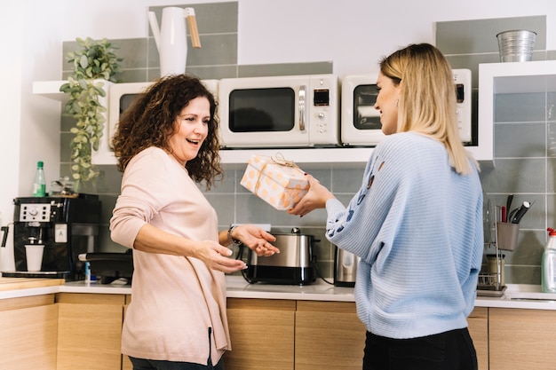 Mulher jovem, dar, presente, para, mãe, em, cozinha