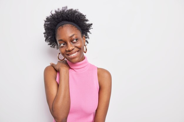 Mulher jovem, de aparência agradável, de pele escura, com uma expressão alegre e sonhadora focada longe