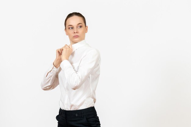 Mulher jovem de blusa branca de frente para o escritório, apenas de pé no fundo branco.