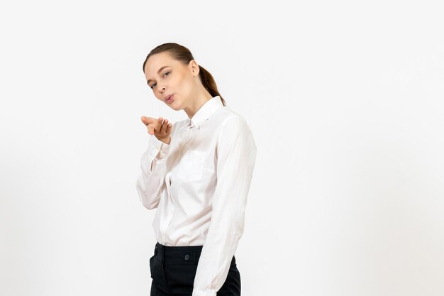 Mulher jovem de blusa branca enviando beijos no ar no fundo branco trabalho de escritório emoção feminina de frente