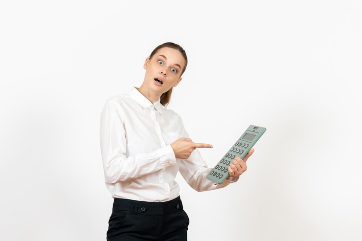 Foto grátis mulher jovem de blusa branca segurando uma calculadora enorme no fundo branco emoção feminina sentimento trabalho de escritório