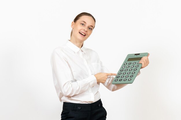 Foto grátis mulher jovem de blusa branca segurando uma calculadora enorme no fundo branco.