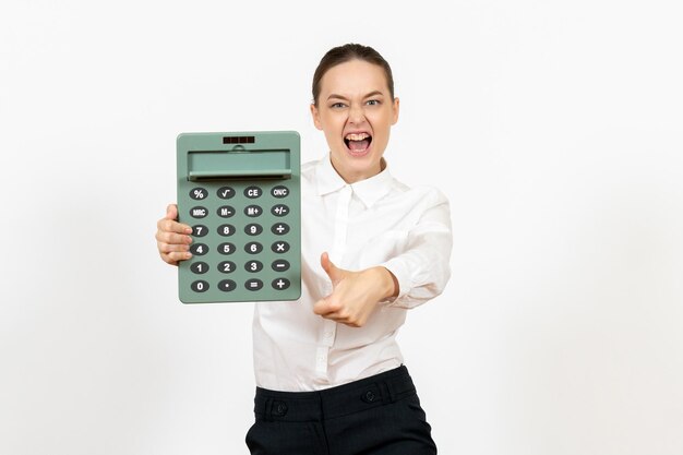 Mulher jovem de blusa branca segurando uma calculadora grande e gritando no fundo branco.