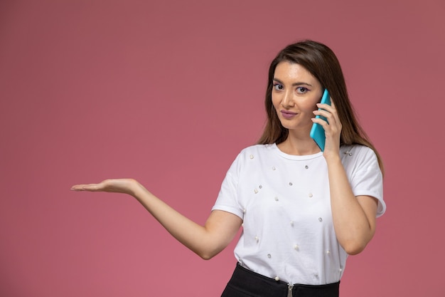 Foto grátis mulher jovem de camisa branca falando ao telefone na parede rosa de frente