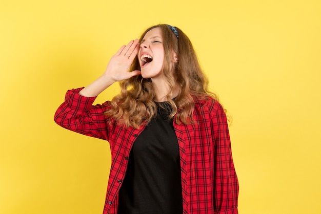 Mulher jovem de camisa quadriculada vermelha posando e gritando sobre fundo amarelo emoções femininas cor modelo humano mulher de frente