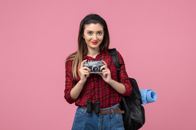 Mulher jovem de camisa vermelha com a câmera na mesa rosa modelo foto mulher de frente