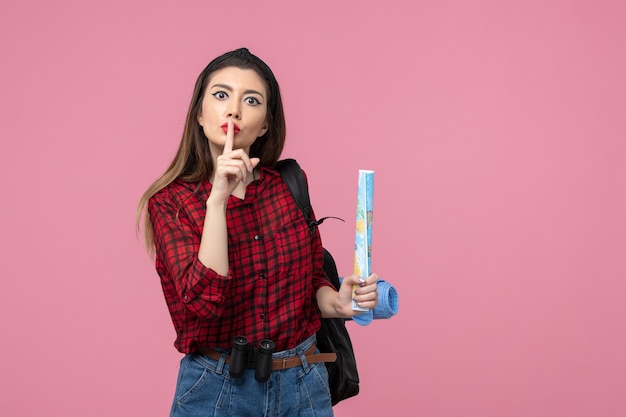 Mulher jovem de camisa vermelha com mapa na cor de fundo rosa moda feminina de frente