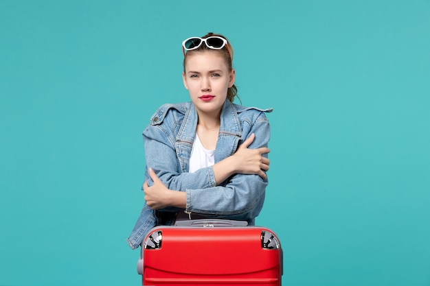 Mulher jovem de casaco azul, se preparando para a viagem e posando no espaço azul