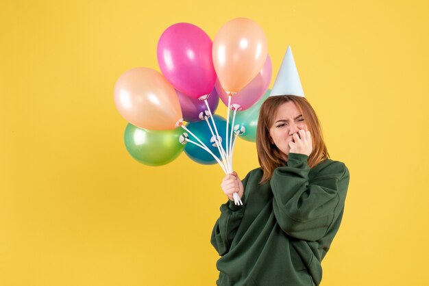 Mulher jovem de frente com balões coloridos estressada