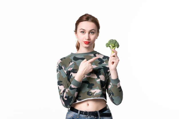 Mulher jovem de frente com brócolis verde sobre fundo branco almoço corpo refeição horizontal salada comida dieta saúde prato