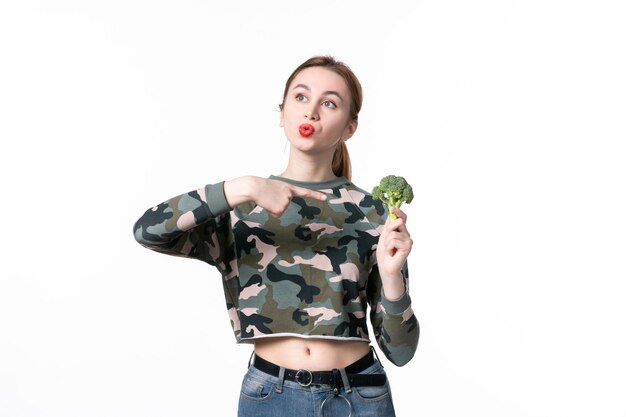 Mulher jovem de frente com brócolis verde sobre fundo branco corpo dieta saúde refeição horizontal almoço prato salada comida