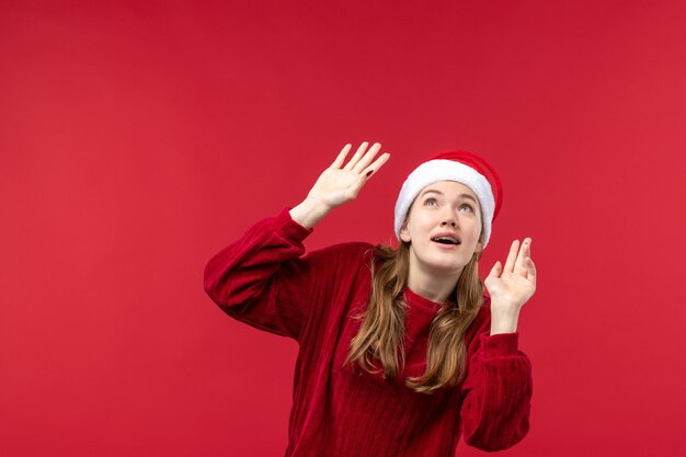 Mulher jovem de frente com expressão animada na mesa vermelha, feriado de Natal vermelho