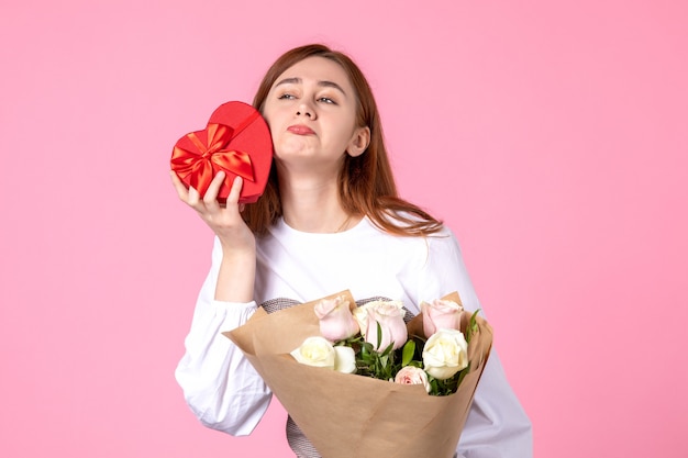 Mulher jovem de frente com flores e presente como presente de dia das mulheres em fundo rosa horizontal março igualdade data rosa mulher amor sensual