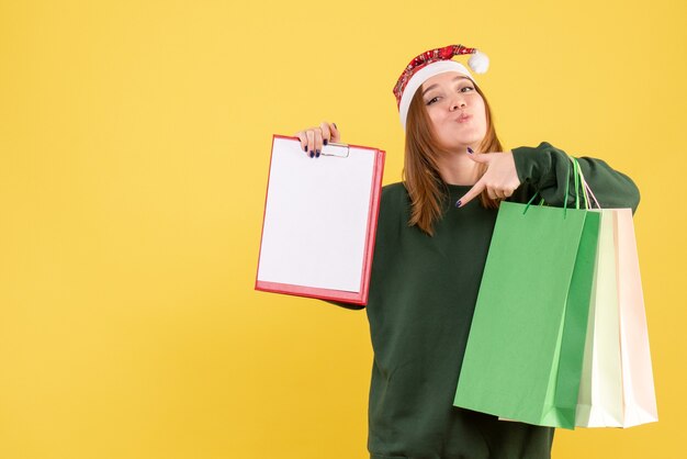 Mulher jovem de frente com nota de arquivo e pacotes de compras