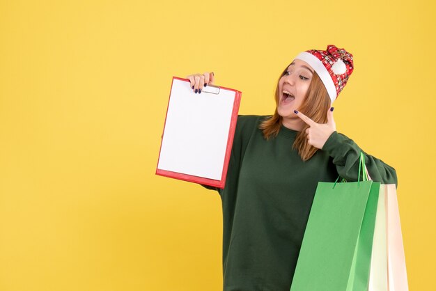 Mulher jovem de frente com nota de arquivo e pacotes de compras