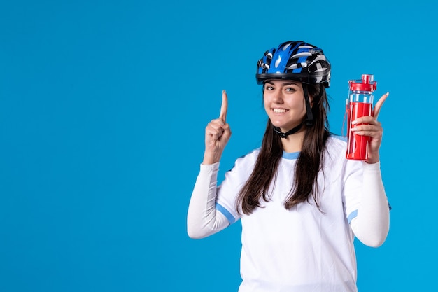 Foto grátis mulher jovem de frente com roupas esportivas e capacete na parede azul