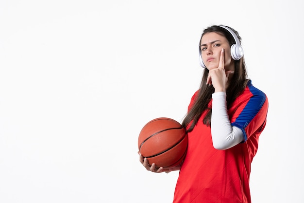 Mulher jovem de frente com roupas esportivas e parede branca de basquete