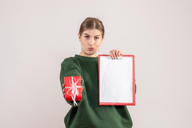 Mulher jovem de frente com um pequeno presente de natal e uma nota