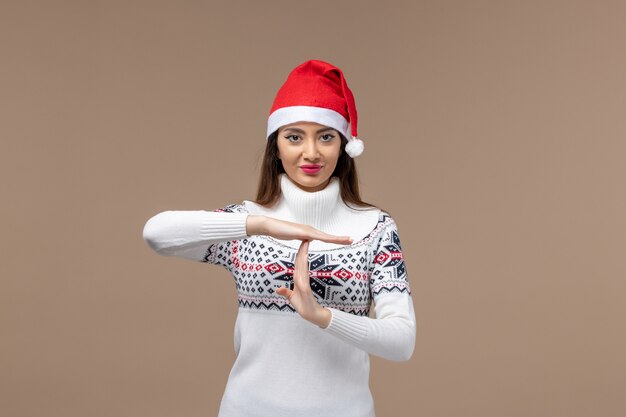 Mulher jovem de frente mostrando a letra t no fundo marrom emoção feriado de natal