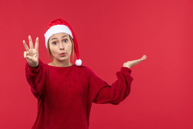 Mulher jovem de frente mostrando número, vermelho feriado natal