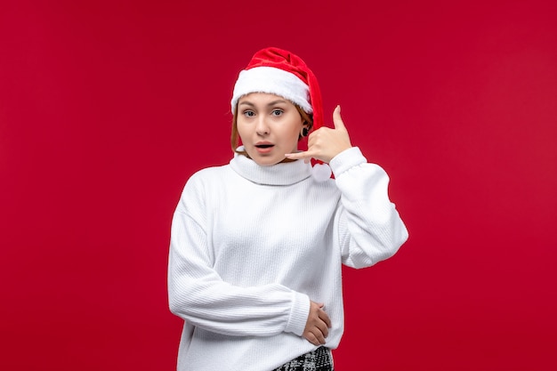 Mulher jovem de frente mostrando pose de telefonema em fundo vermelho