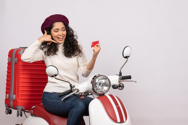 Mulher jovem de frente para a bicicleta segurando um cartão do banco vermelho no fundo branco cidade cor estrada veículo motocicleta velocidade férias dinheiro
