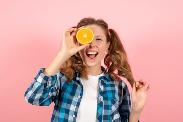 Mulher jovem de frente para a camisa quadriculada azul posando com laranja no fundo rosa mulher emoção humana modelo moda garota