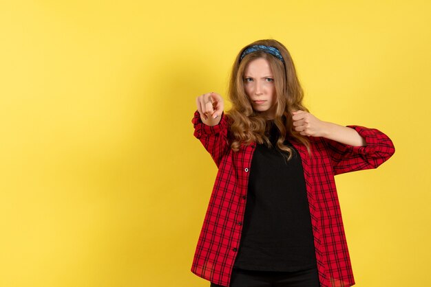 Mulher jovem de frente para a camisa quadriculada vermelha em pé e posando no fundo amarelo modelo meninas mulher humana cor emoção